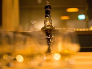 Whisky station set up with bottle of Cask Islay against blurred out dram glasses 