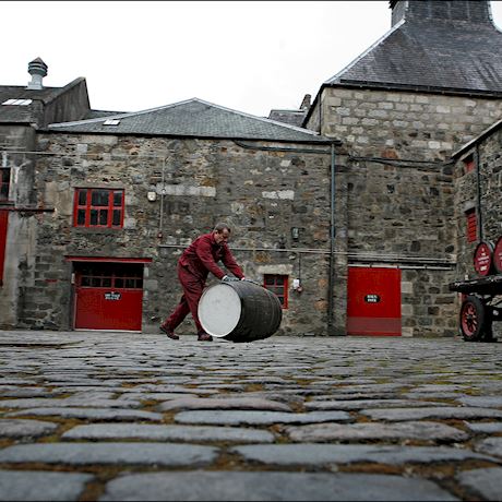 a man rolling a whisky barrel