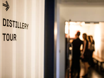 Distillery Tour sign with evening guests in the tour start area